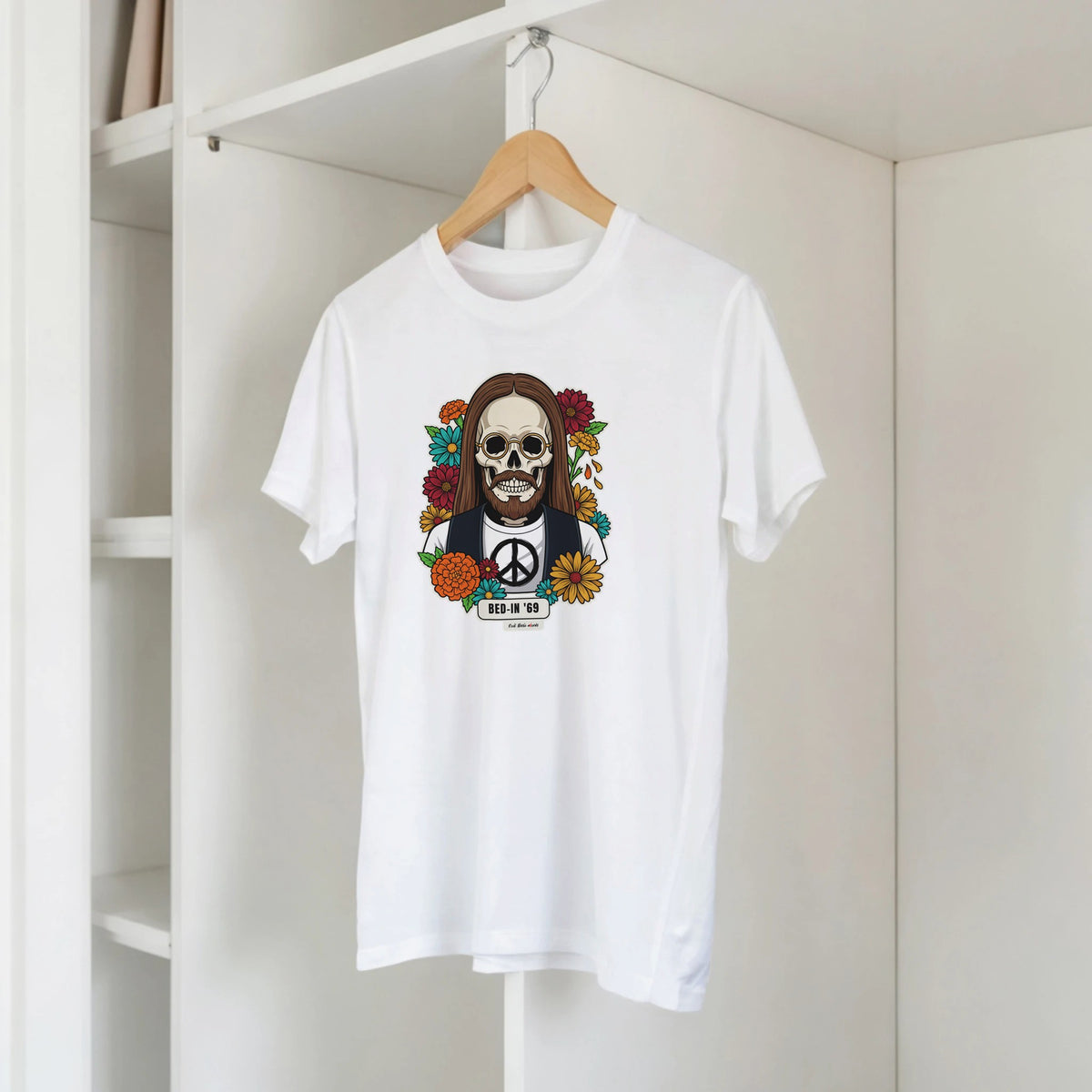 T-shirt bianca con la calavera Bed-In '69 su una gruccia di legno, appesa a una libreria bianca