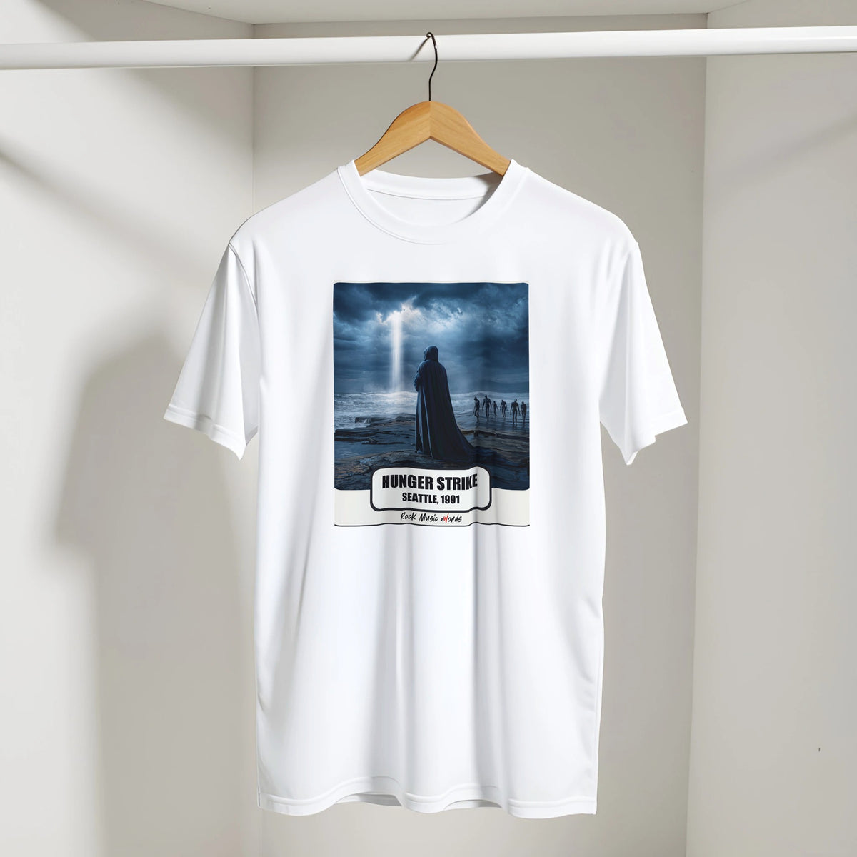 T-shirt bianca con la stampa Rock Art «Hunger Strike – Seattle, 1991» appesa a una gruccia di legno, dentro un armadio bianco