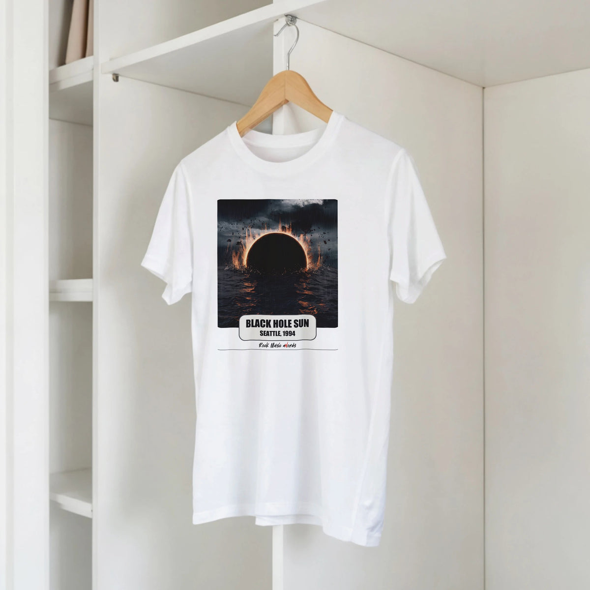 T-shirt bianca con la stampa Rock Art «Black Hole Sun – Seattle, 1994» su una gruccia di legno, appesa a una libreria bianca