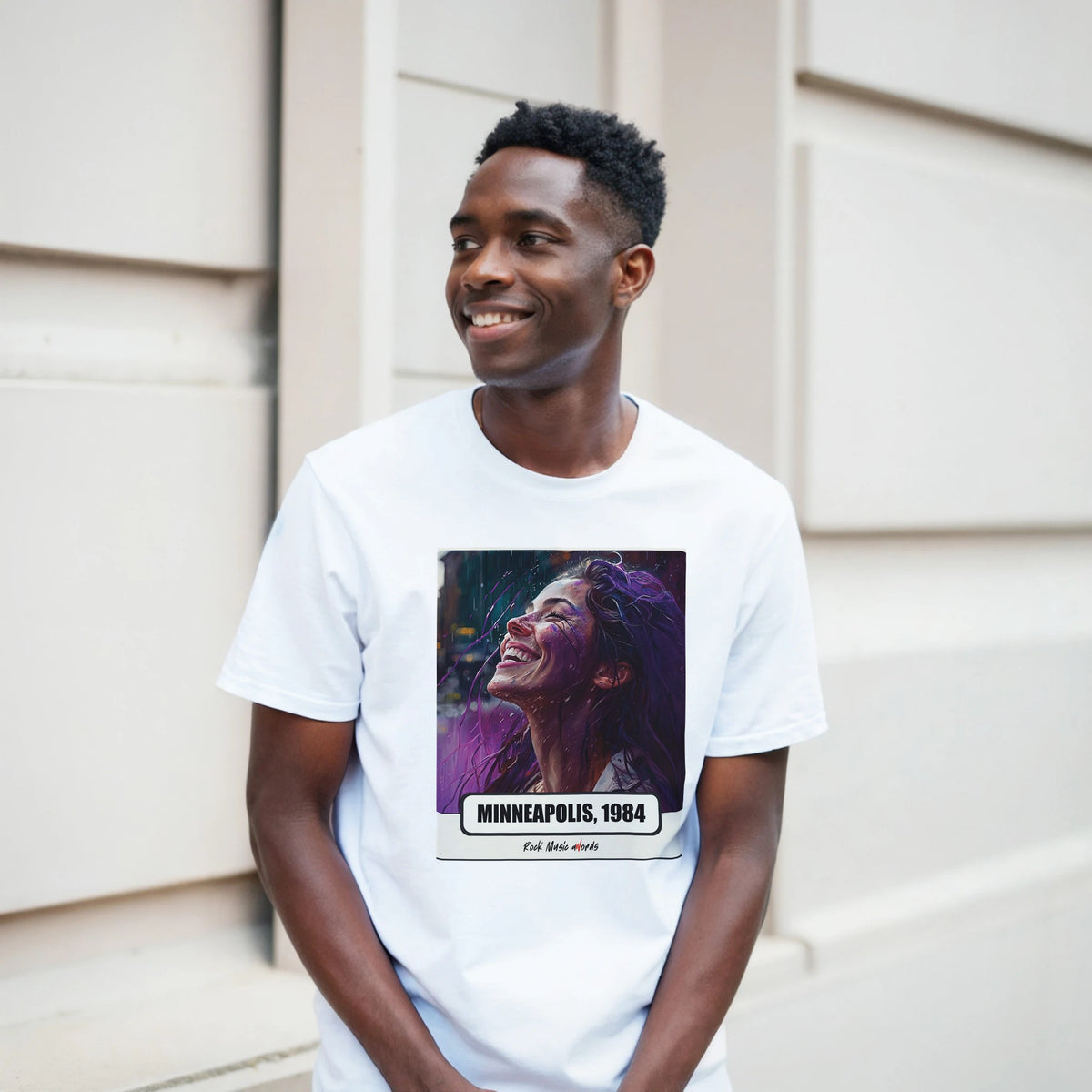Ragazzo sorridente davanti a un muro chiaro a blocchi indossa la t-shirt bianca con la stampa Rock Art «Purple Rain – Minneapolis, 1984»