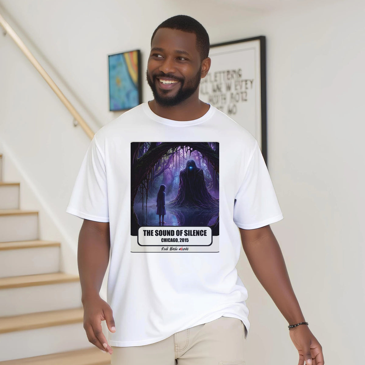 Uomo con la barba sorride vicino a una scala di legno, in casa, e indossa la t-shirt bianca con la stampa Rock Art «The Sound of Silence – Chicago, 2015»