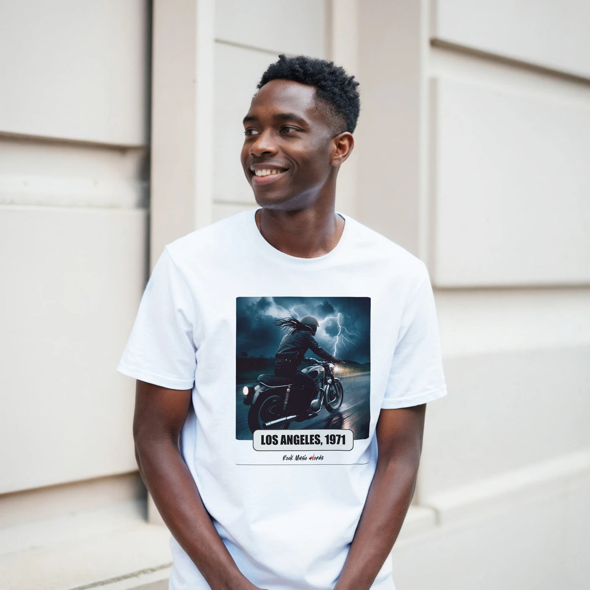 Ragazzo sorridente davanti a un muro chiaro a blocchi indossa la t-shirt bianca con la stampa Rock Art «Riders on the Storm – Los Angeles, 1971»