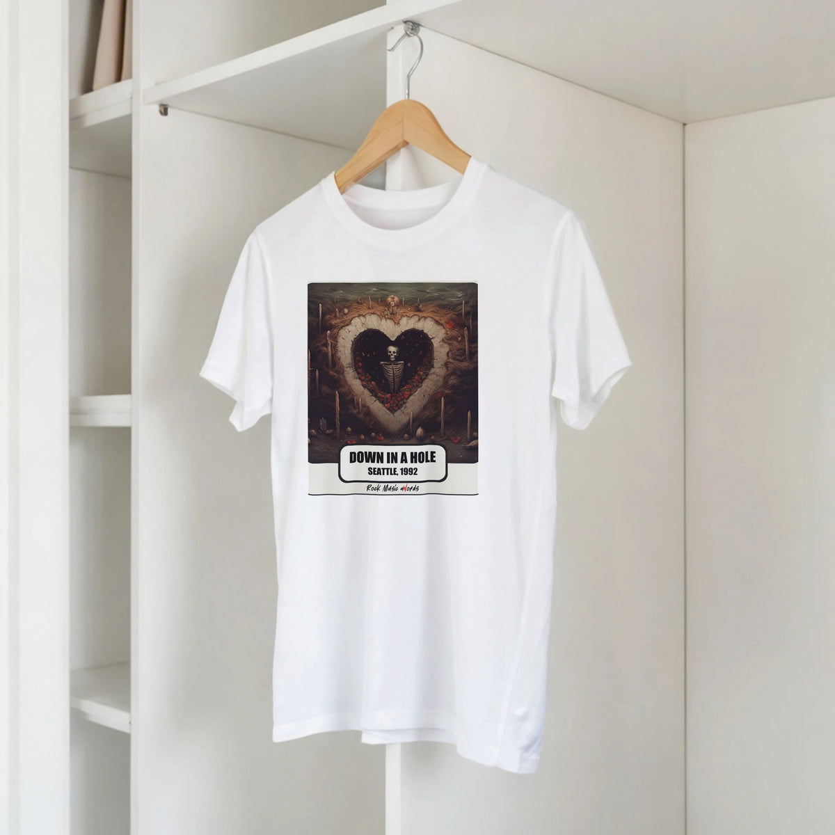 T-shirt bianca con la stampa Rock Art «Down in a Hole – Seattle, 1992» su una gruccia di legno, appesa a una libreria bianca