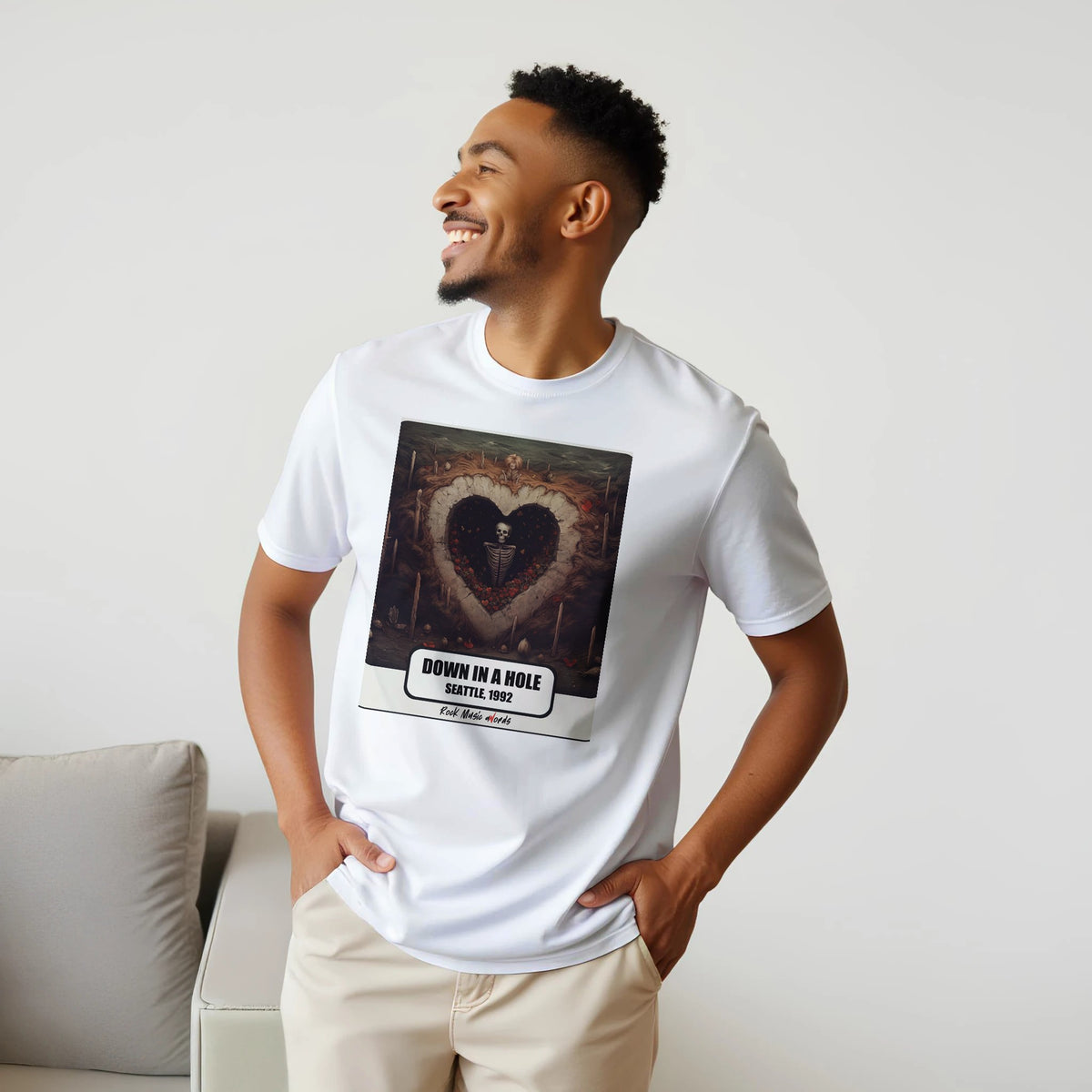 Uomo sorridente con le mani sui fianchi, accanto a un divano, indossa la t-shirt bianca con la stampa Rock Art «Down in a Hole – Seattle, 1992»