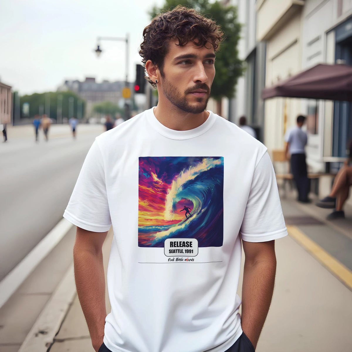 Uomo con capelli ricci e barba su un marciapiede di città indossa la t-shirt bianca con la stampa Rock Art «Release – Seattle, 1991»