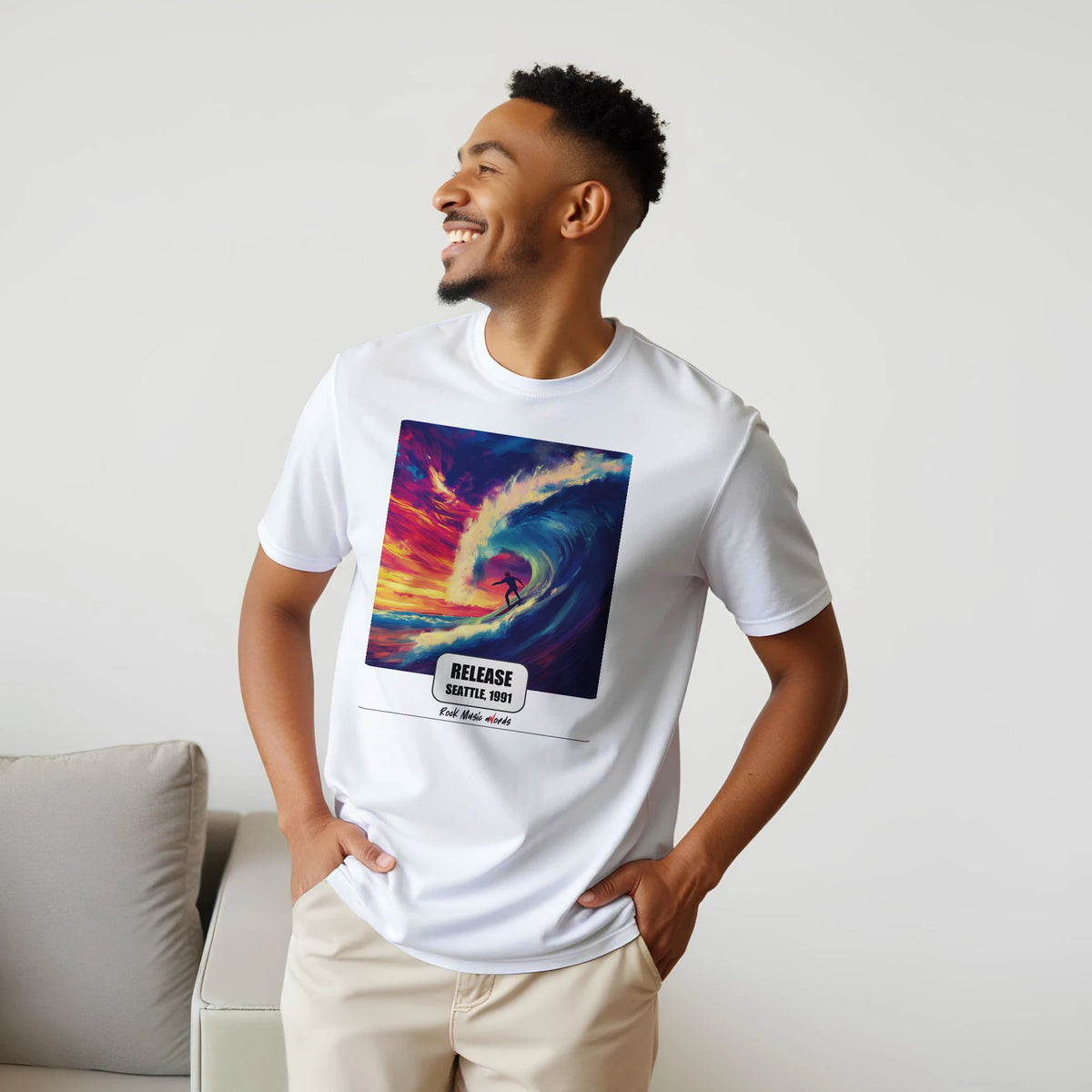 Uomo sorridente con le mani sui fianchi, accanto a un divano, indossa la t-shirt bianca con la stampa Rock Art «Release – Seattle, 1991»