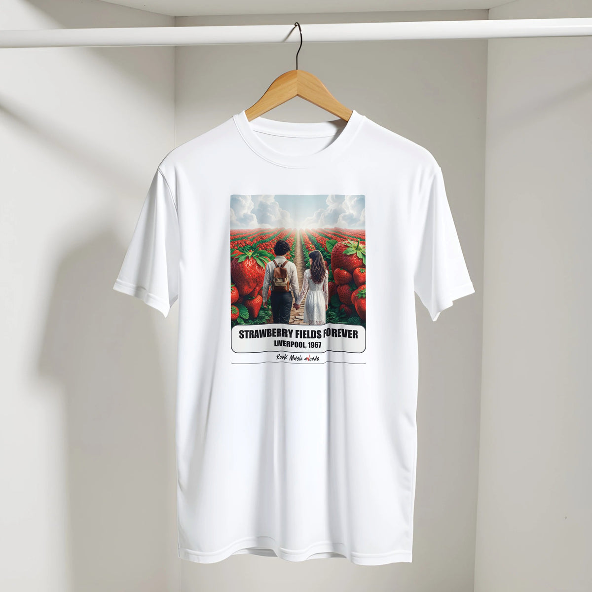 T-shirt bianca con la stampa Rock Art «Strawberry Fields Forever – Liverpool, 1967» appesa a una gruccia di legno, dentro un armadio bianco
