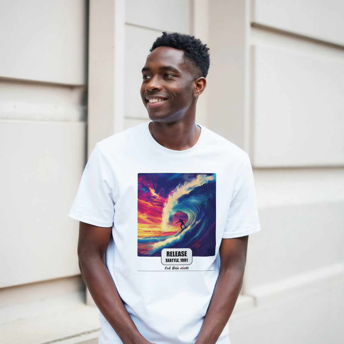 Ragazzo sorridente davanti a un muro chiaro a blocchi indossa la t-shirt bianca con la stampa Rock Art «Release – Seattle, 1991»