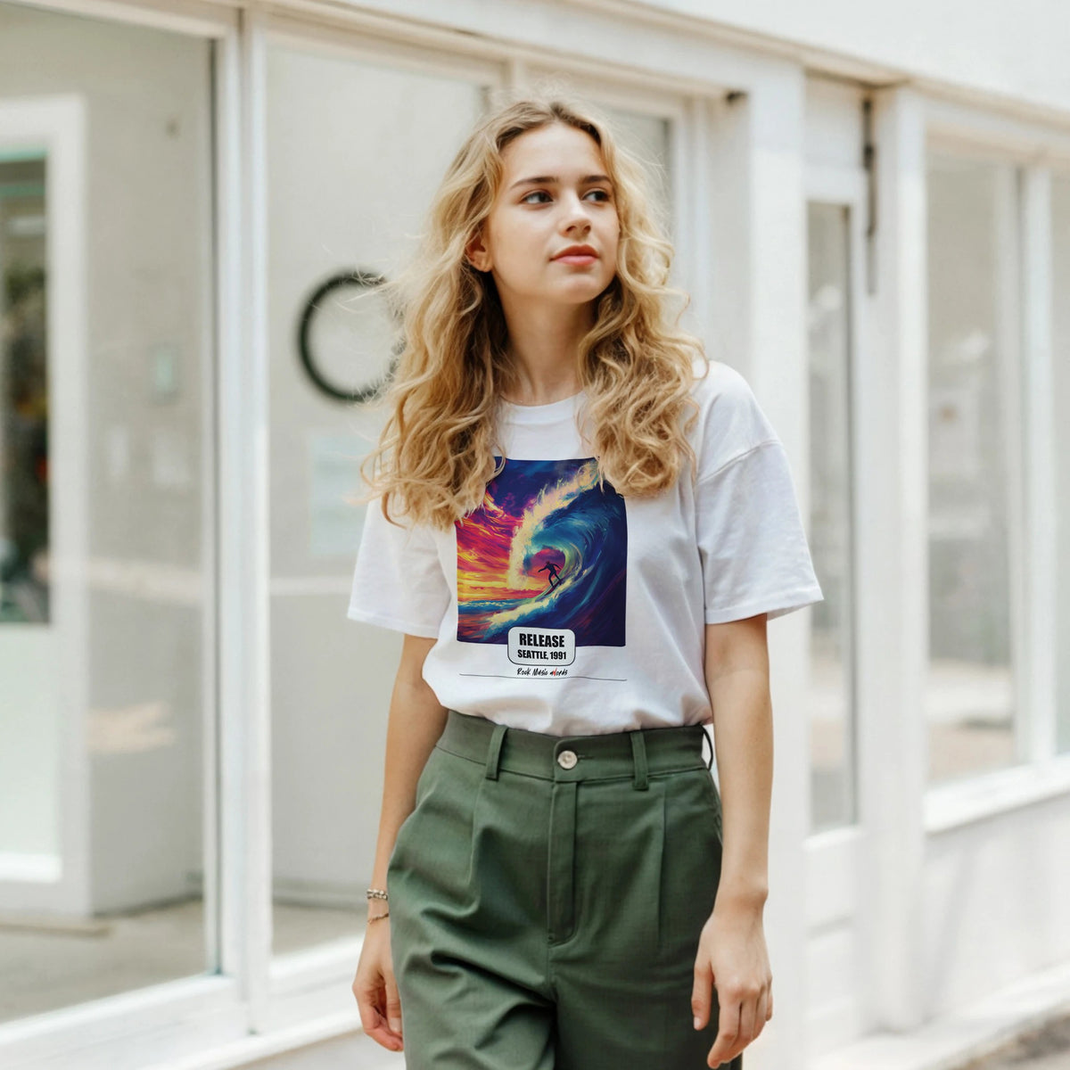 Ragazza bionda davanti a una facciata a vetrate indossa la t-shirt bianca con la stampa Rock Art «Release – Seattle, 1991» e pantaloni verdi