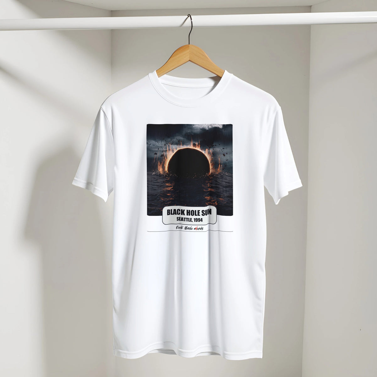 T-shirt bianca con la stampa Rock Art «Black Hole Sun – Seattle, 1994» appesa a una gruccia di legno, dentro un armadio bianco