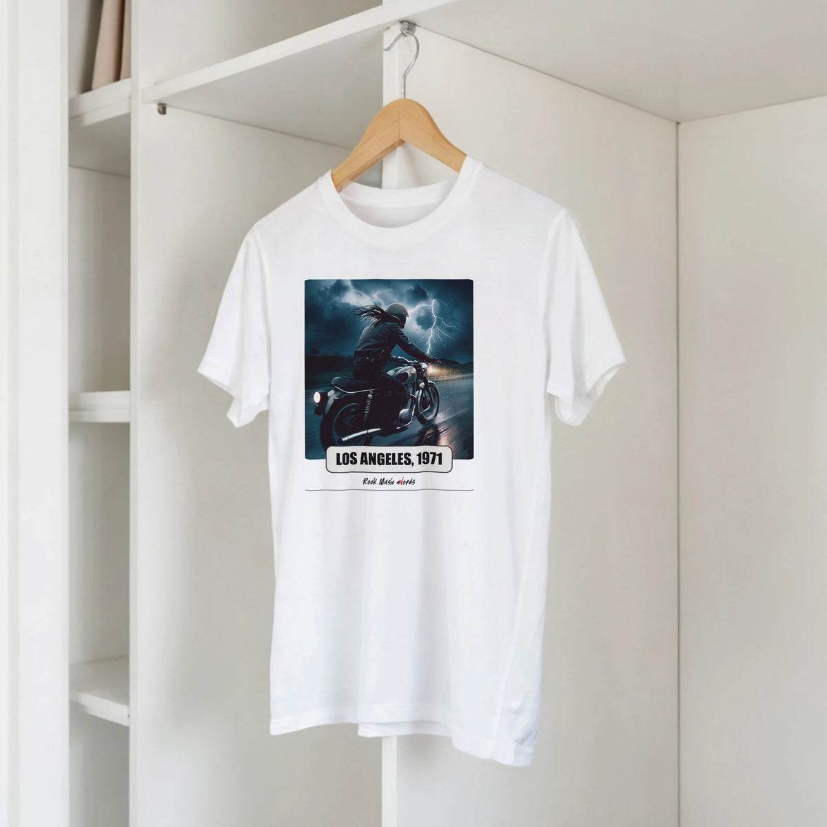 T-shirt bianca con la stampa Rock Art «Riders on the Storm – Los Angeles, 1971» su una gruccia di legno, appesa a una libreria bianca