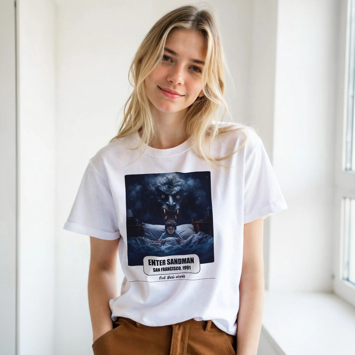 Ragazza bionda con le mani in tasca, accanto a una finestra, indossa la t-shirt bianca con la stampa Rock Art «Enter Sandman – San Francisco, 1991»