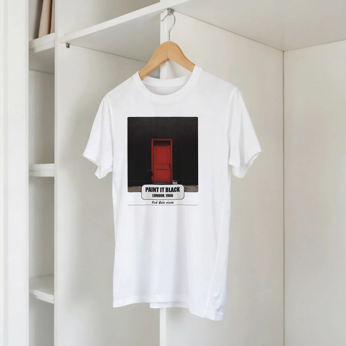 T-shirt bianca con la stampa Rock Art «Paint It Black – London, 1966» su una gruccia di legno, appesa a una libreria bianca