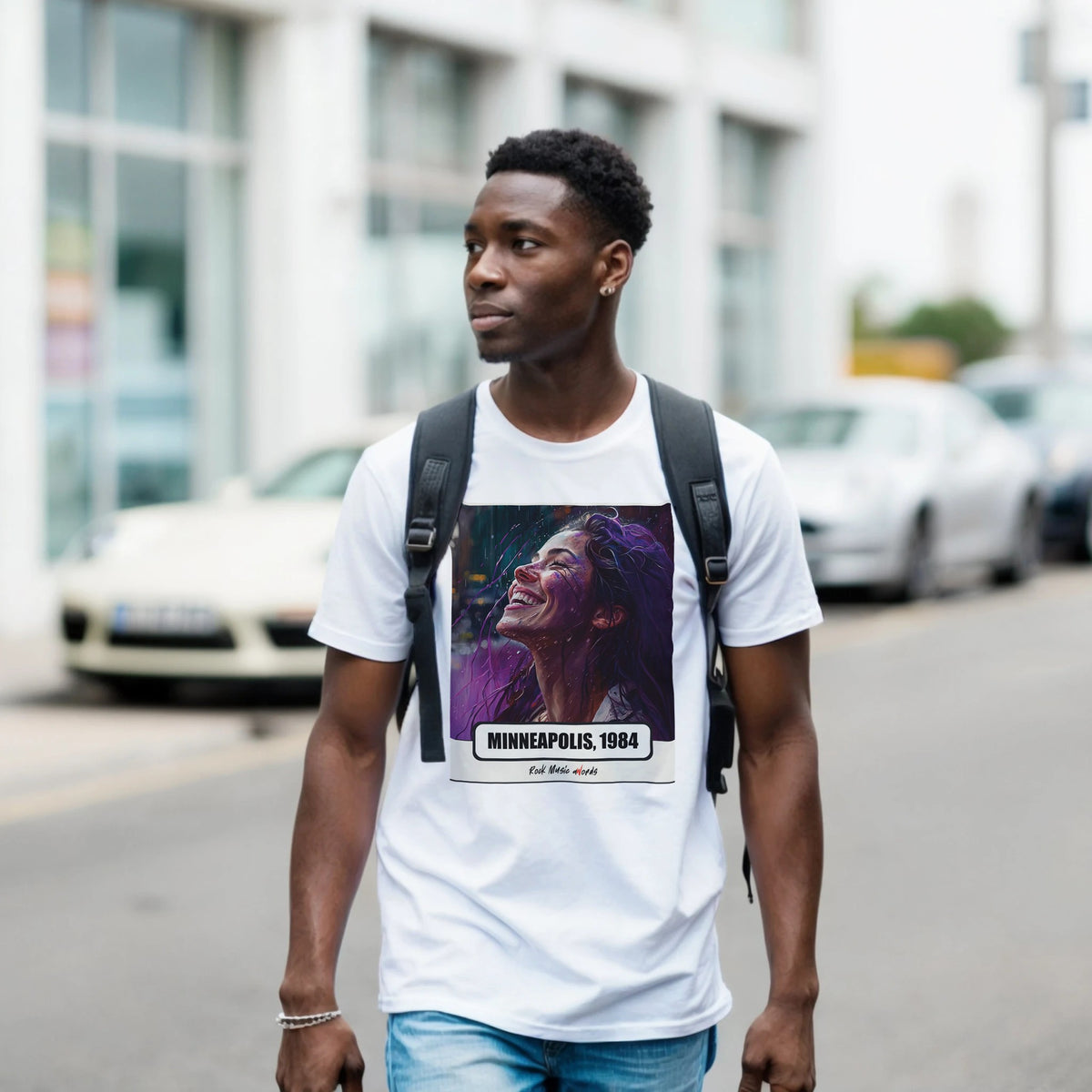 Ragazzo con zaino nero e jeans cammina per una via di città indossando la t-shirt bianca con la stampa Rock Art «Purple Rain – Minneapolis, 1984»