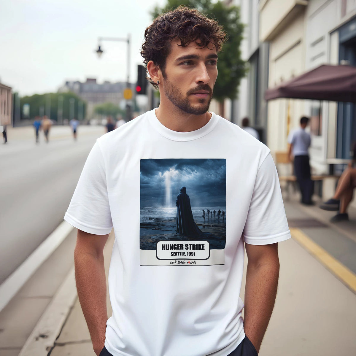 Uomo con capelli ricci e barba su un marciapiede di città indossa la t-shirt bianca con la stampa Rock Art «Hunger Strike – Seattle, 1991»