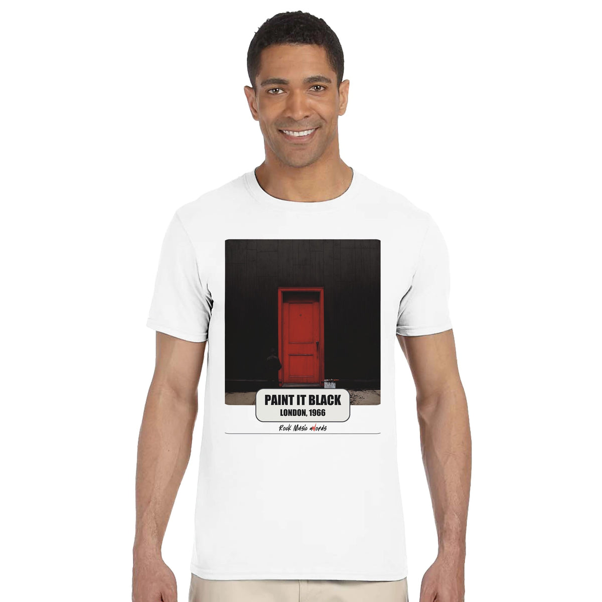 Uomo sorridente in piedi su fondo bianco indossa la t-shirt bianca con la stampa Rock Art «Paint It Black – London, 1966»