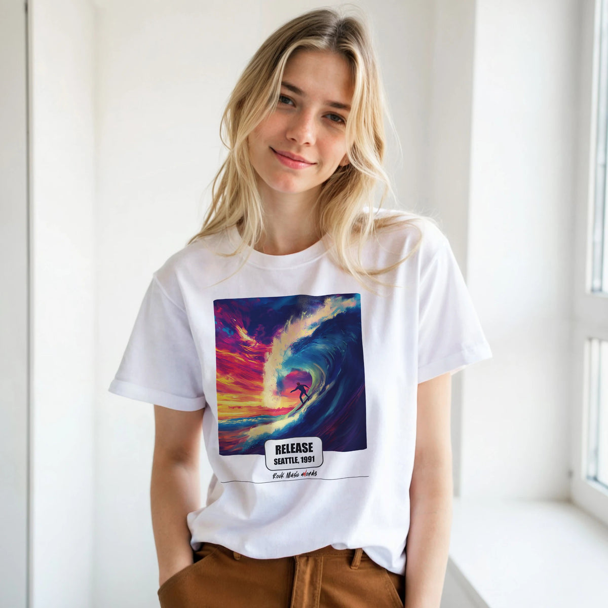 Ragazza bionda con le mani in tasca, accanto a una finestra, indossa la t-shirt bianca con la stampa Rock Art «Release – Seattle, 1991»