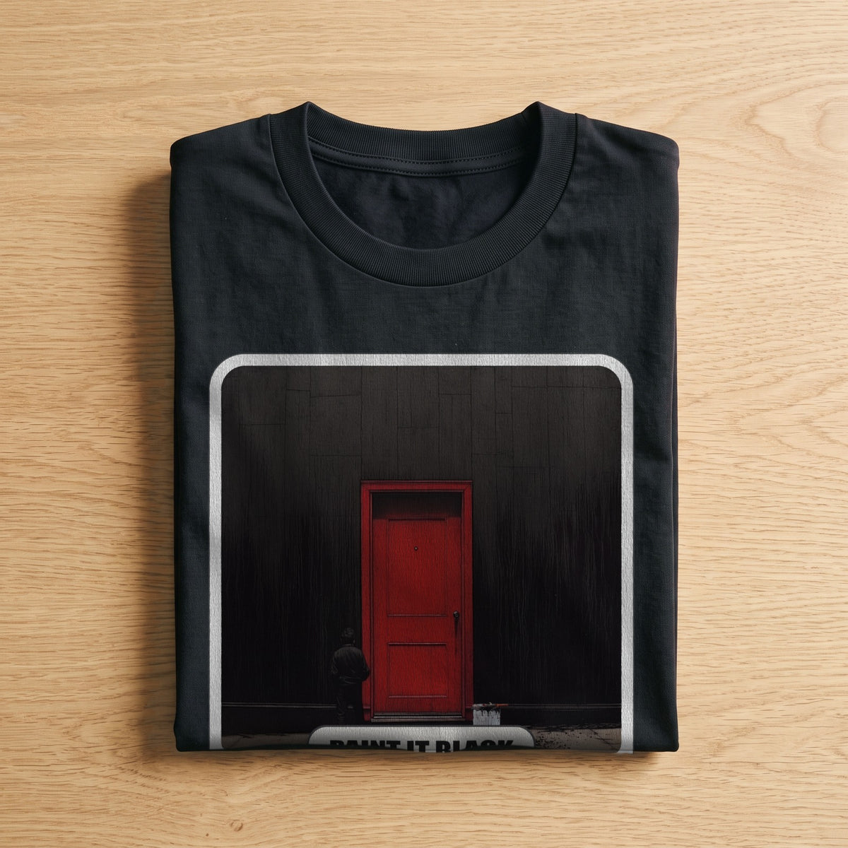 La t-shirt nera «Paint It Black – London, 1966» piegata su un piano di legno, come arriva a casa (ricostruzione al computer)