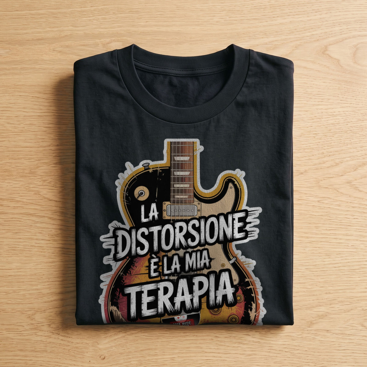 La t-shirt nera «La distorsione è la mia terapia» piegata su un piano di legno, come arriva a casa (ricostruzione al computer)