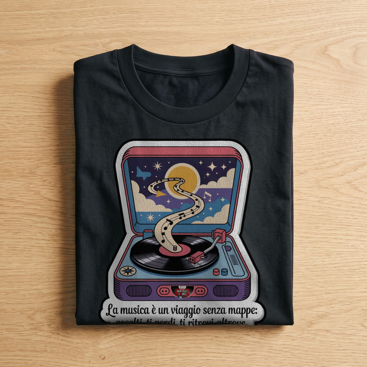La t-shirt nera «La musica è un viaggio senza mappe» piegata su un piano di legno, come arriva a casa (ricostruzione al computer)