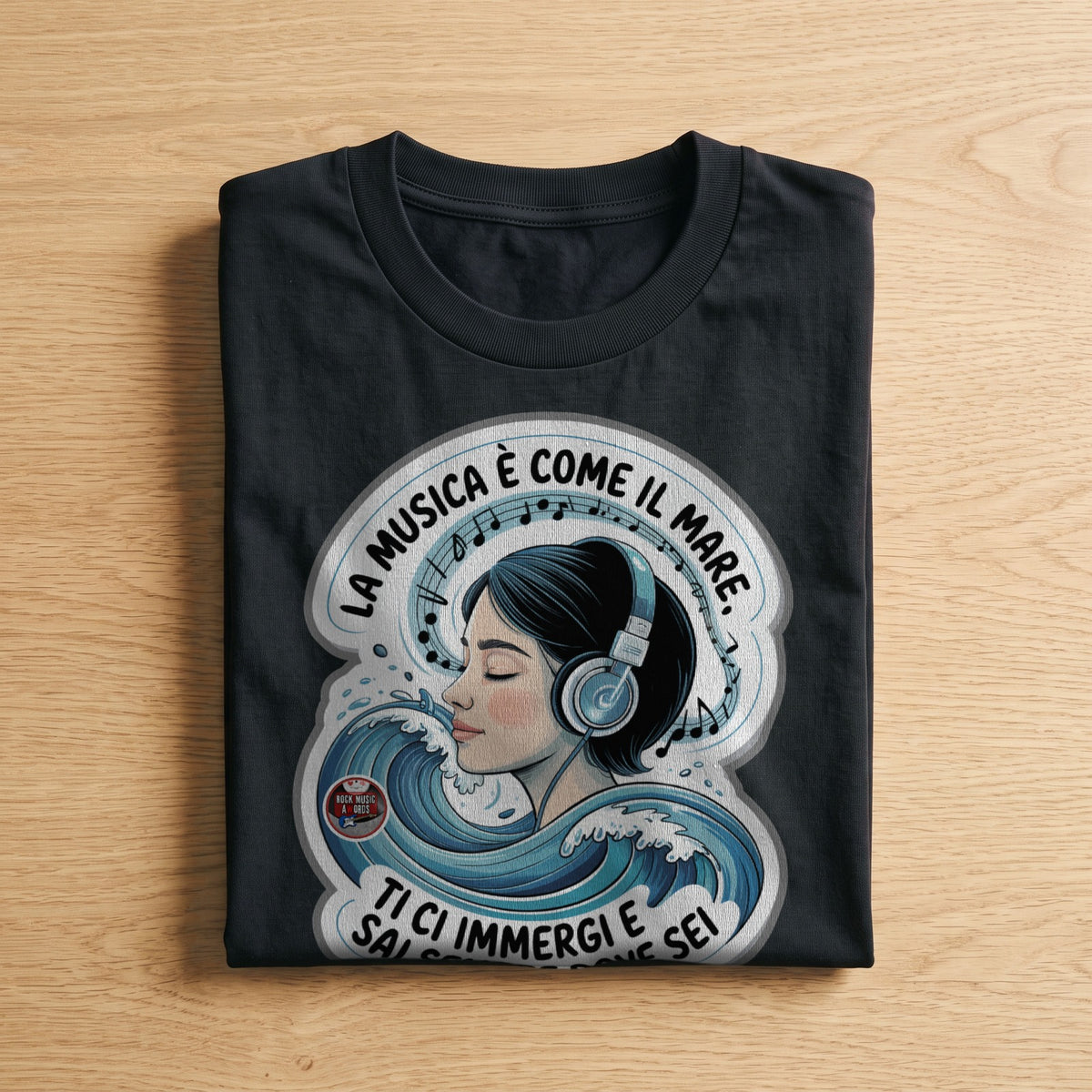 La t-shirt nera «La musica è come il mare: ti ci immergi e sai sempre dove sei» piegata su un piano di legno, come arriva a casa (ricostruzione al computer)